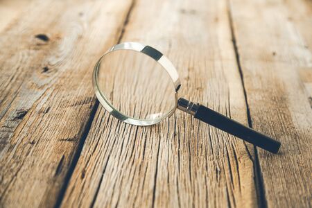 magnifier on the brown wooden desk backgroundの写真素材