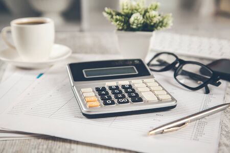 calculator with coffee on the document on deskの写真素材