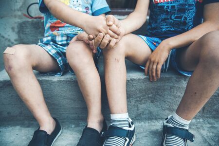 two boys injured leg sitting in the streetの写真素材