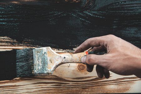 man hand black paint and brush on woodの写真素材