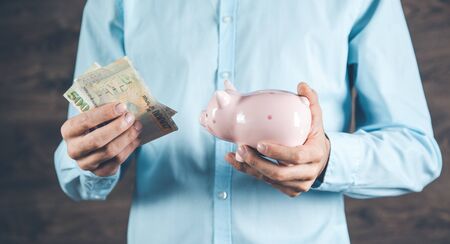man hand holding  money and piggy bank