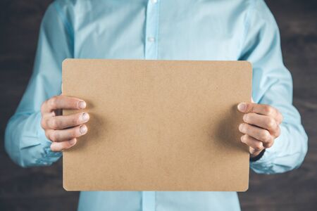man hand holding brown paper on dark backgroundの写真素材
