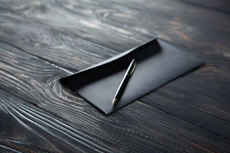 black envelope with pen on the black wooden deskの写真素材
