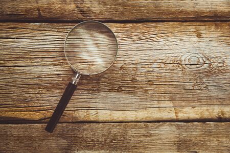 magnifier on the brown wooden desk backgroundの写真素材