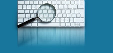 magnifier on white keyboard on blue backgroundの写真素材