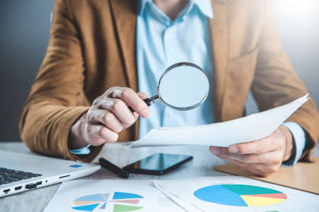 man hand magnifier with document on deskの写真素材