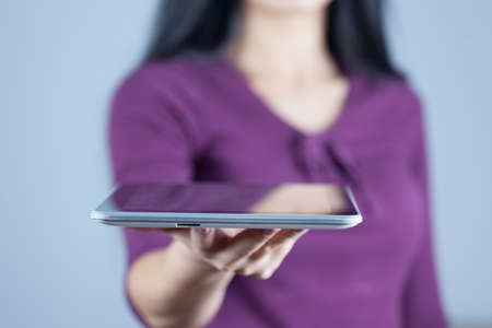 young woman hand holding tablet on gray backgroundの写真素材