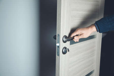 young man opening room door on brown backgroundの写真素材