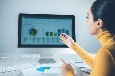 woman working in computer with graph in officeの写真素材