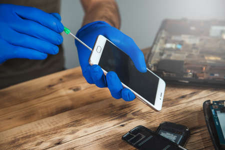 Technician repairing mobile phone at table