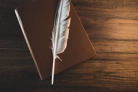 feather on book on the wooden tableの写真素材