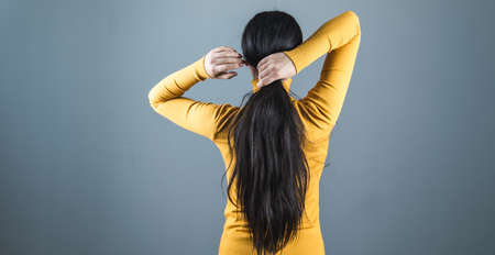 woman tie the hair on gray background