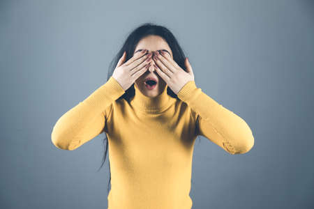 surprised woman hand close eye on gray backgroundの写真素材