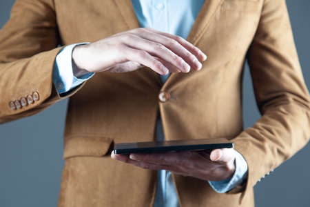 man hand holding tablet on gray backgroundの写真素材