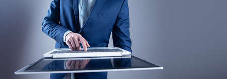 business man hand holding computer on gray backgroundの写真素材