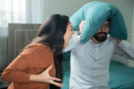 man head pillow with angry woman on bedの写真素材
