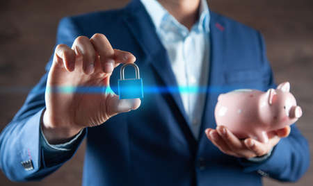 man hand holding lock with piggy bankの写真素材