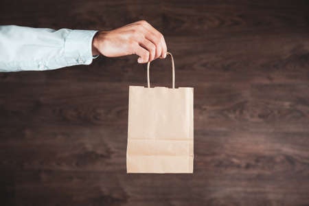 man hand shopping bag on brown background