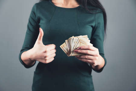 woman hand holding money and okay sign on gray backgroundの写真素材
