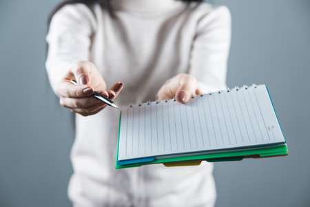 woman hand holding pen and notepad on gray backgroundの写真素材
