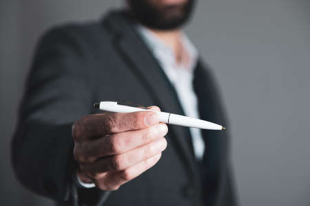 man hand holding white pen on gray backgroundの写真素材