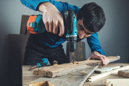 worker man hand electric drill wirh wood