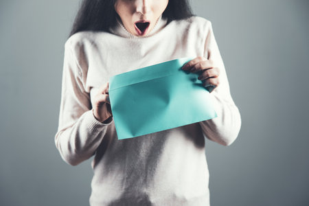 woman hand holding letter on gray backgroundの写真素材
