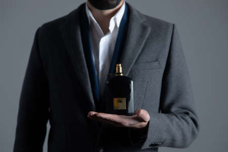 man hand holding perfume bottle on dark backgroundの写真素材