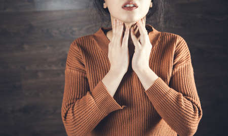 woman hand in ache throat on dark backgroundの写真素材