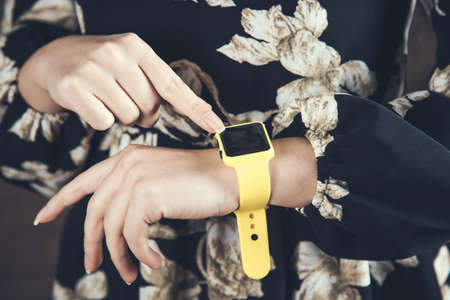 woman hand yelow smart watch on dark background