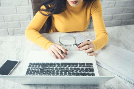 woman hand magnifier and computer on tableの写真素材