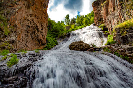 waterfall and rock with trees aunder abstract sky