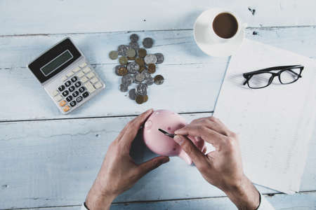man hand coins and piggy bank with calculator on the tableの写真素材