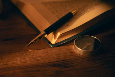 pen and book with compass on the table