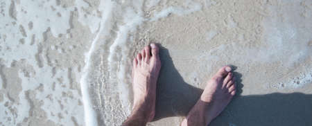 young man feet on the beach on the sandの写真素材