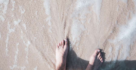 young man feet on the beach on the sandの写真素材