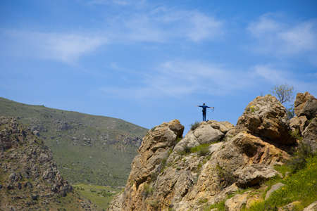 traveling happy man standing on a high rockの写真素材