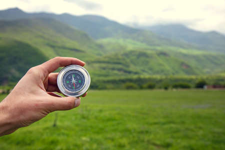man hand compass in the mountain background