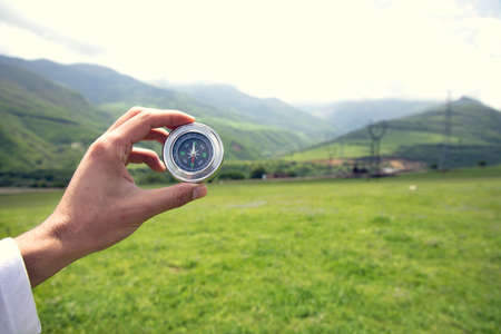 man hand compass in the mountain background