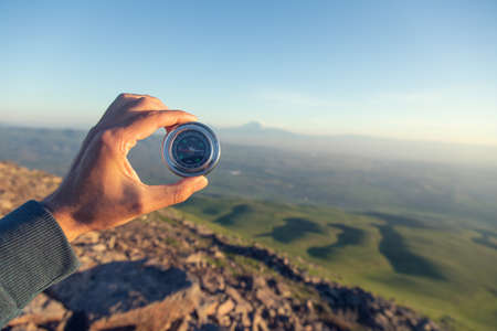 man hand compass in mountain at the sunsetの写真素材