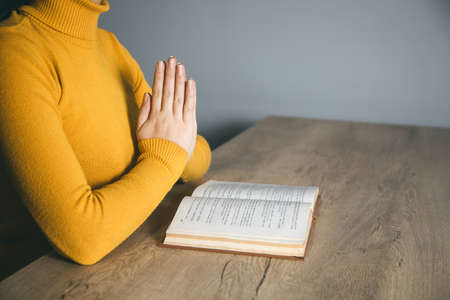 praying woman hand book in dark roomの写真素材