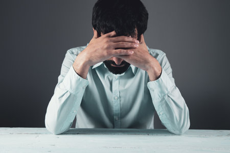 sad man hand in head on table background
