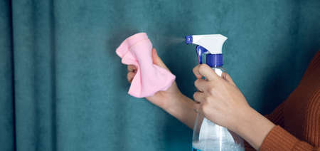 woman hand holding cleaning fluid and cloth