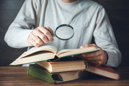 man hand magnifier and books on the tableの写真素材