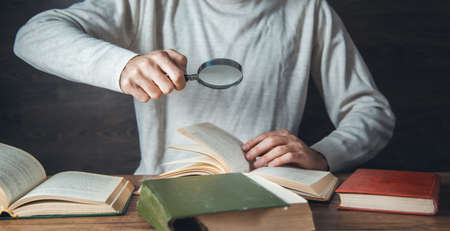 man hand magnifier and books on the tableの写真素材
