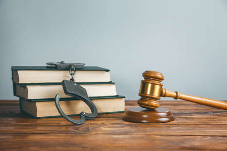 judge and handcuffs on book on the tableの写真素材