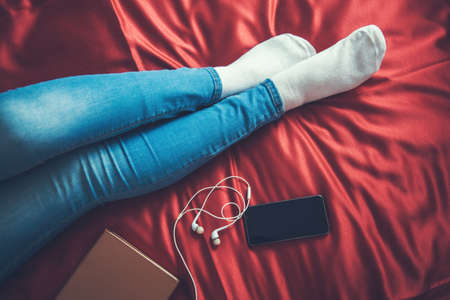 young woman hand phone in red bedの写真素材