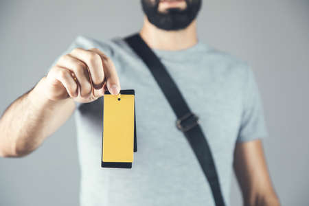 young fashion man hand holding yellow tagの写真素材