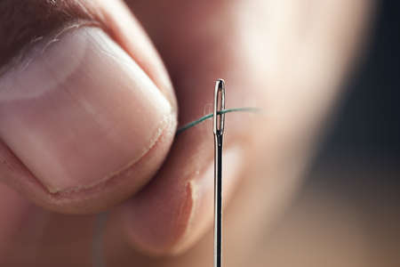 the man threads the needle on dark background
