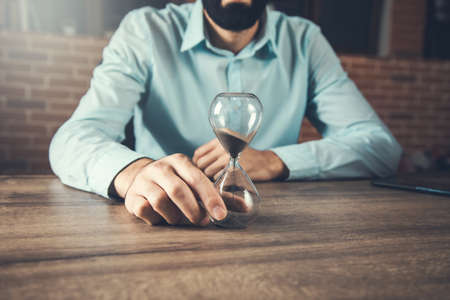Businessman with hourglass on the wooden deskの写真素材